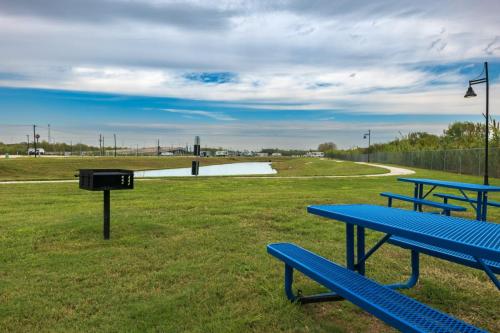 A barbecue grille stands next to a blue metal picnic table at the far edge of the fishing lake at the Medical Center RV Resort in Houston, Texas. 