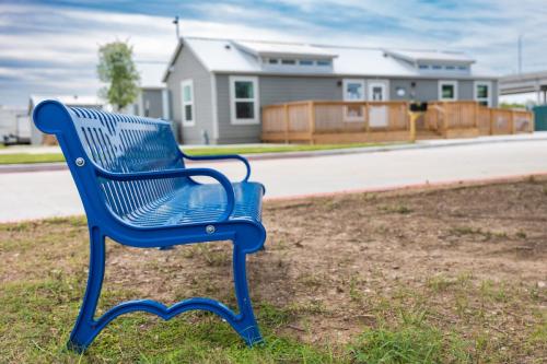 An empty blue park bench sits along the roadside out front of the main office of the Medical Center RV Resort in Houston, Texas. 